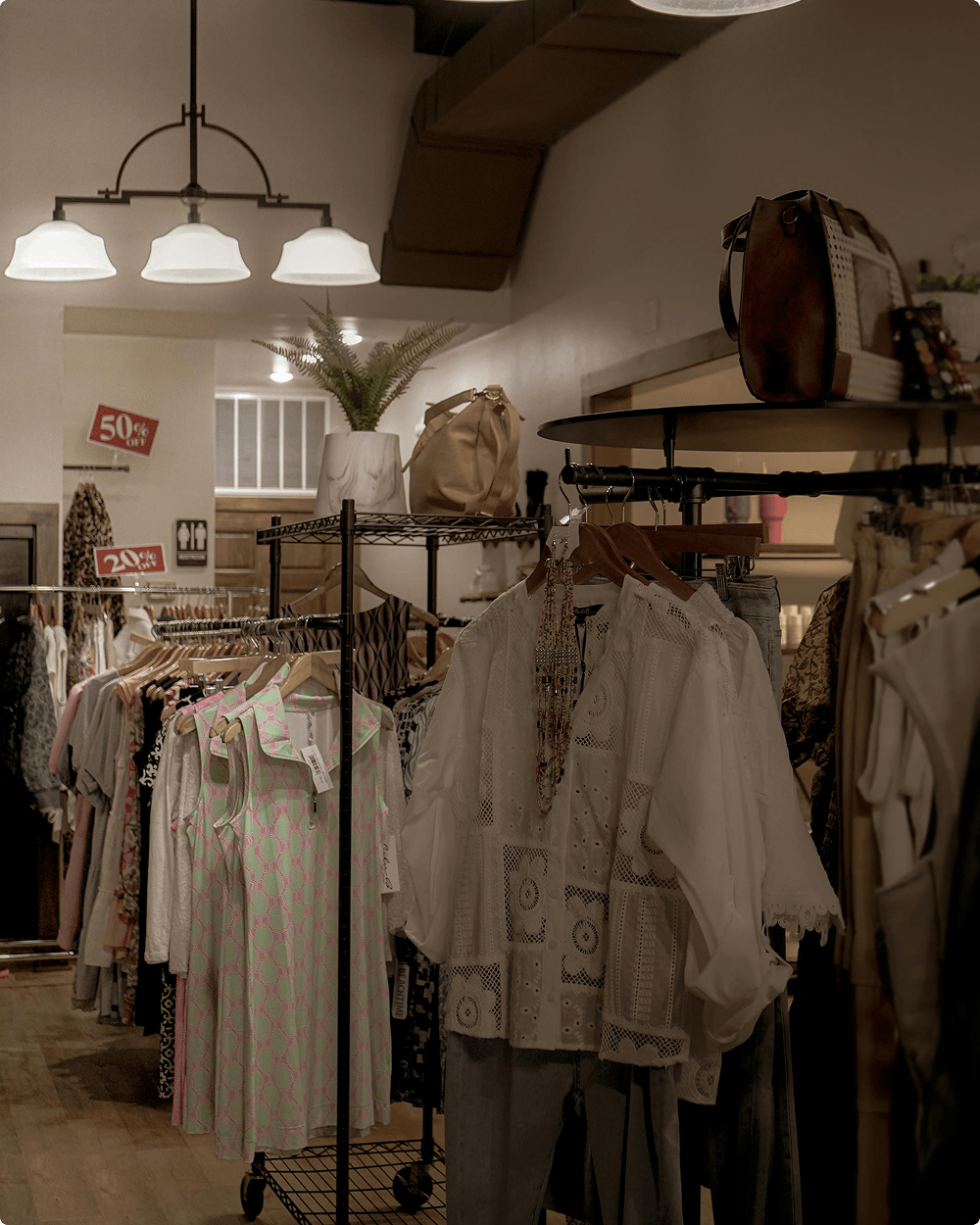 Interior cálido de boutique de moda con prendas elegantes en perchas bajo luz suave